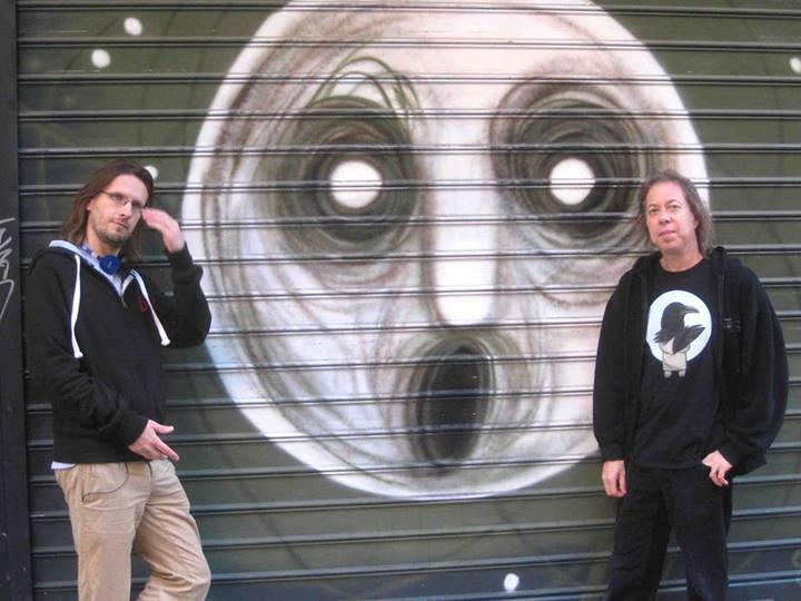 At first glimpse, this might merely appear to be a photo of Steven Wilson and Adam Holzman standing by the painting of The Raven cover in front of Sun Records in Madrid.  But look closer at Steven&rsquo;s neck.  (I need to know which headphones those are&hellip;they look cute.)  Now look at the cord dangling out from under his jacket and into his pocket.
Unless Steven&rsquo;s pockets are actually Time Lord pockets and he&rsquo;s got a portable LP player in there, I think it&rsquo;s pretty safe to say we&rsquo;ve just caught him red-handed using an mp3 player.  Sure, it might just be there to function as a headset for his phone, but you don&rsquo;t usually pick headphones over an earpiece unless you also intend to also listen to music with them.
Save this photo so you can haul it out if he ever mentions iPods in an interview again.
(I know, I know, I haven&rsquo;t been around much recently.  The Tumblr dash is absolute murder in terms of system resources, and when you couple that with my half-dead laptop fan, it&rsquo;s really not a good idea for me to hang out here much until my fan gets replaced.  And yes, I know I missed doing a birthday post for SW earlier this week, but at least I still left the obligatory post on his FB wall.)