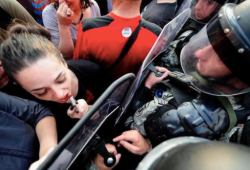 sixpenceee:  A woman protestor in Macedonia uses a riot shield as a mirror to reapply her lipstick.