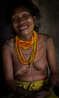 A Mentawai woman displaying traditional tattoo and sharpened teeth, rather happyVia As Worlds Divide.