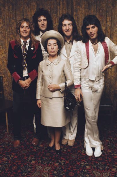 blondebrainpower:Queen And Pretender. British rock band Queen posing with actress and Queen Elizabeth II look-alike, Jeannette Charles, September 1974. The group are (left to right) drummer Roger Taylor, guitarist Brian May, bassist John Deacon and singer