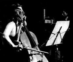 Cellist Charlotte Moorman performs Opera Sextronique by Nam June Paik (right) where score calls for topless soloist in gas mask, 1967.