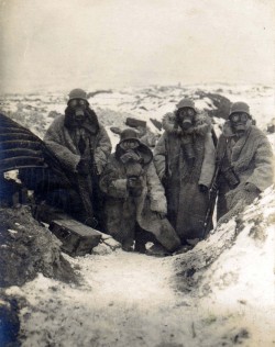 militaryarmament:  Four German soldiers wearing fur coats and gas masks posing in a trench, c. 1917. 