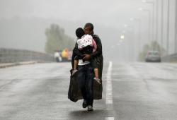 unrar:    A Syrian refugee kisses his son as he walks through a rainstorm towards Greece’s border with Macedonia, near the Greek village of Idomeni, Yannis Behrakis. 
