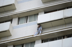 A patient sits outside a hospital building in Changsha, Hunan province, China, on June 25, 2014. Firefighters saved the patient who broke a window on the eighth floor and attempted suicide. The patient was sent to the hospital after a car accident and