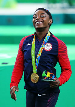 celebritiesofcolor:  Simone Biles simles with her gold medal after the medal ceremony for the Artistic Gymnastics Women’s Team on Day 4 of the Rio 2016 Olympic Games at the Rio Olympic Arena on August 9, 2016 in Rio de Janeiro, Brazil. 