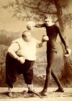 Two Victorian sideshow performers boxing – the fat man and the thin man.