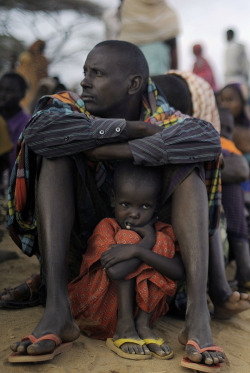 awkwardsituationist:   photo by tony karumba of a somali girl taking shelter under her father as they queue for a meal at the dadaab refugee camp in eastern kenya. they were displaced by drought and the consequent famine which occurred two summers ago