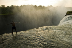 unrar:  Looking over the edge of Victoria Falls from a swimming hole, Zambia, Annie Griffiths. 