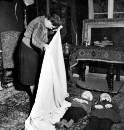 German woman using sheet to cover bodies of 2 children who were killed by their mother who then killed herself after hearing that her husband had lost his life fighting on the outskirts of the city after its liberation by Allied forces, 1945, by Margaret