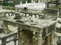 Unknown Artist, Graveyard, Sculpture Above Grave, early 20th c. Graveyard is a sculptural installation in a public cemetery. Urban legend dictates that it is made for a family that was poisoned during dinner. In each chair the name of the family member