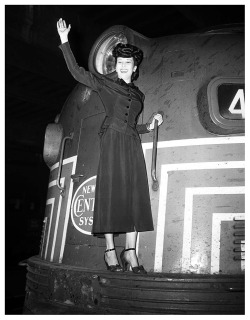 Satira     (aka. Patricia Schmidt) Vintage press photo from the late-1940&rsquo;s, captures Satira in Chicago; posing on the prow of a New York Central locomotive.. Part of a series of photos likely taken sometime after her return from Cuba, where