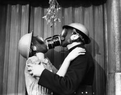 memories65:  A couple wearing gas masks kisses under mistletoe, London December 1940. (Fox Photos/Getty Images)