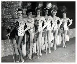 Vintage candid 50’s-era photograph of a sextet of leggy showgirls posing on stage, at an unidentified theatre..