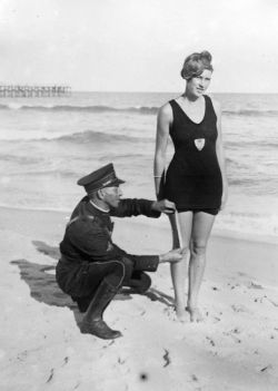 blondebrainpower: 1925 “Smokey” Buchanan from the West Palm Beach police  force, measuring the bathing suit of Betty Fringle on Palm Beach, to  ensure that it conforms with regulations introduced by the beach  censors.  Image: General Photographic
