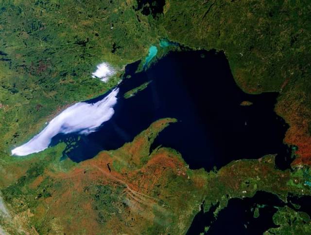 Satellite image of Lake Superior with some of the surrounding land colored orange and red from fall colors on trees. Credit: NOAA Great Lakes CoastWatch node.