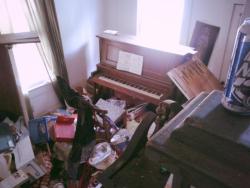 Piano in abandoned house. Sheets of music untouched despite the chaos that surrounds.