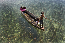 Children ride on a boat on the crystal clear lake in Sabah, Malaysia. 