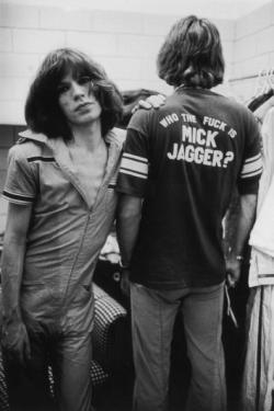 weinribs:    Mick Jagger leans on his stylist Pierre Laroche during the Rolling Stones Tour of the Americas, 1975. Laroche wears a t-shirt with the slogan ‘Who the Fuck is Mick Jagger?’. Photo by Christopher Simon  