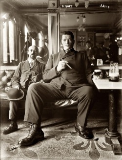 Baptiste Hugo (of les Géants des Alpes) 7 foot 6.5 inches tall enjoys a cigar and an adult beverage c.1908.