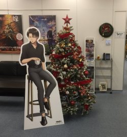 SnK News: Happy Holidays at Wit StudioSnK Chief Animation Director Asano Kyoji shared two photos of the current WIT Studio entrance, featuring a Christmas tree as well as the life-size Levi cardboard stand greeting staff and visitors!The Levi stand is