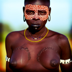 A Mursi girl, decorated with body paint and scarification.