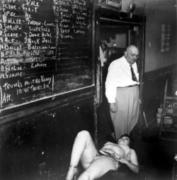 alterneaze: (via This Week’s Weegee #81) A showgirl takes a break Backstage; at an unidentified theatre.. The large chalkboard lists the sequence of acts for the entire Burlesque show.. It also lists a notice: &ldquo;Trunks Must Be Ready..&rdquo; 