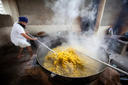 artofprayer:A cook in a Sikh kitchen cooking curry in an extremely large pot.The Sikh kitchen provides tens of thousands of free meals on a daily basis