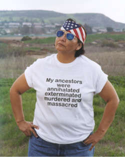 terresauvage:   “Shelley Niro parodies the archetypal tourist tee-shirt from the point of view of First Nations Peoples as an exploration into the lasting effects of European colonialism in North America. Facing the camera directly and poised against
