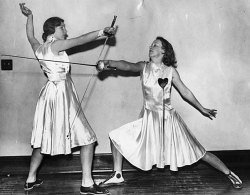 modernfencing:[ID: two women in white dresses, posing with foils. The woman on the right in lunging and her opponent is making a very high parry two. Old, black and white photo.] Lulie Becker and Beatrice Nelson, University of Minnesota fencers in 1953!
