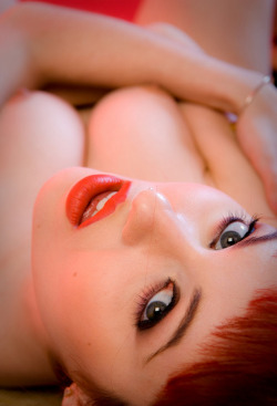 Lovely redhead lying down staring at you, pushing up her breasts.