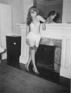 Lynne O'Neill (aka. &ldquo;The Original Garter Girl&rdquo;) poses by the fireplace..