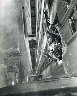 andrewharlow:  A B-25 bomber crashes into the Empire State Building on the morning of July 28, 1945. New York Times photographer Ernie Sisto had two of his friends hold his belt while he dangled off the side of the building to snap this photo.  