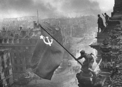 picturesofwar:  This day in history: A flag of the Soviet Union is raised atop the Reichstag by two Soviet soldiers  in a photograph captured by Yevgeny Khaldei, signifying an end to the Battle of Berlin.  Although a flag had been raised two days earlier,