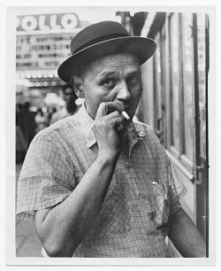 Creator: unidentified photographer Description: Item is a copy print. Romare Bearden smoking a cigarette on 125th street in Harlem, N.Y., with the Apollo theater in the backround. Forms part of: Romare Bearden papers 1937-1982 Citation: Romare Bearden
