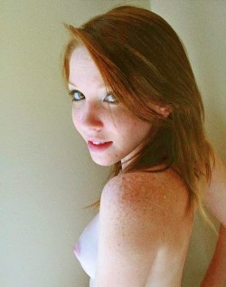 Pretty redhead with freckles, showing her breast.
